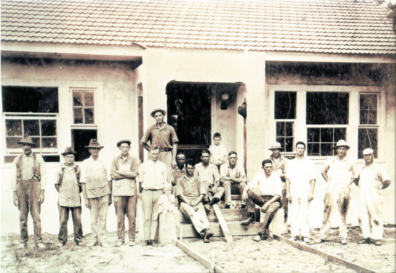 black and white photo of men in front of a house