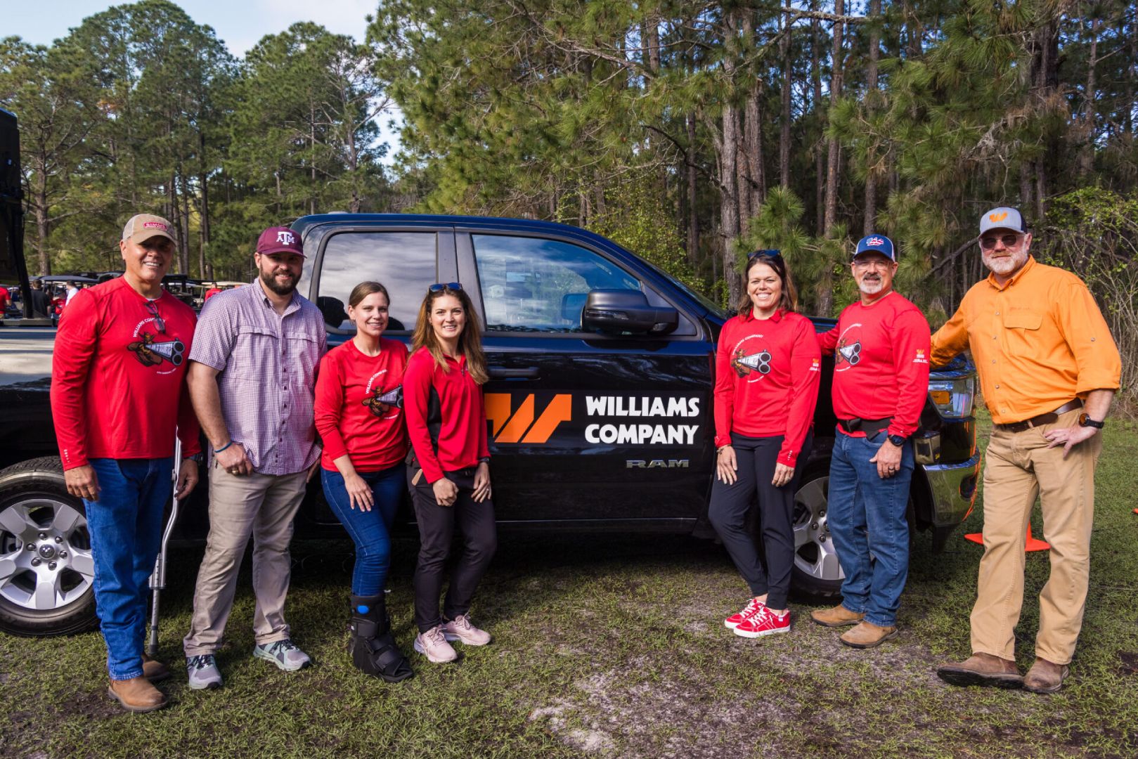 Group of six people posing in front of a black truck.