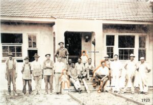 Black and white photo of a group of men building a house in 1923.