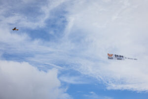 Plane towing banner ad in sky.