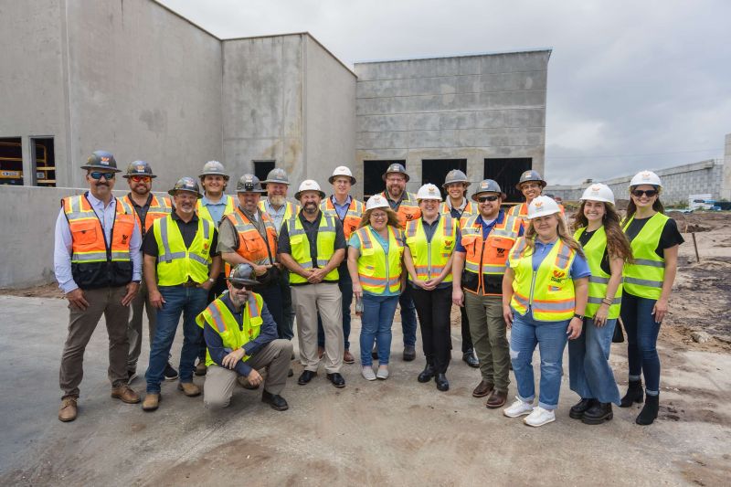 Group of people wearing safety vests and hard hats.