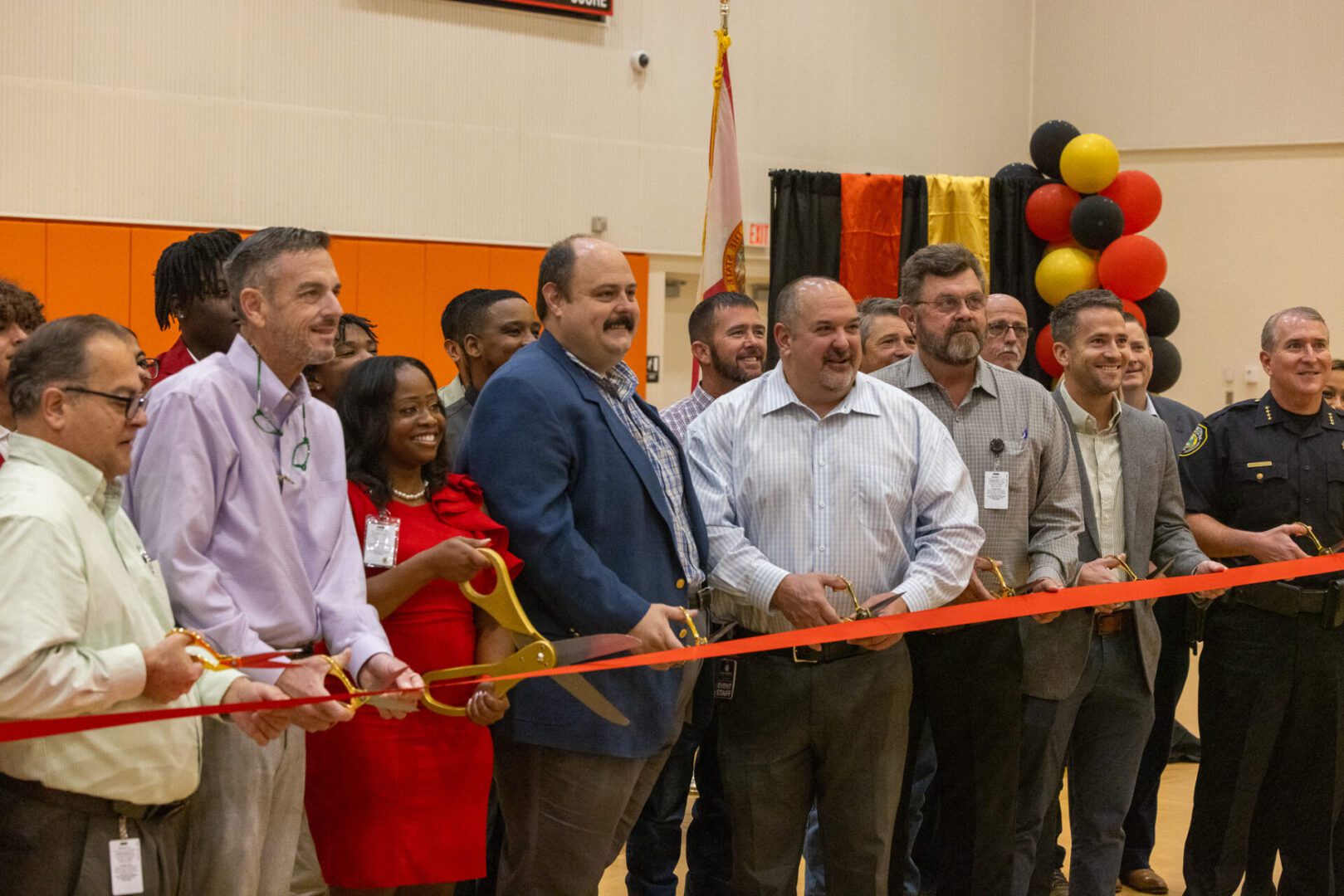 Ribbon cutting ceremony with many people.