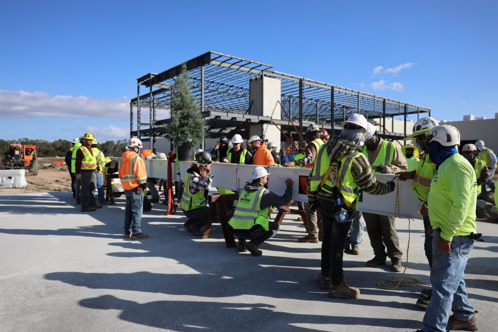 Construction workers assembling a steel framework on a sunny day.