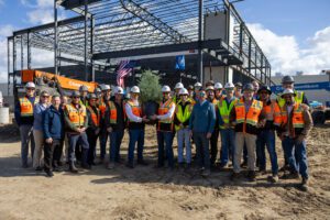 Group of construction workers posing at a building site under a steel framework.