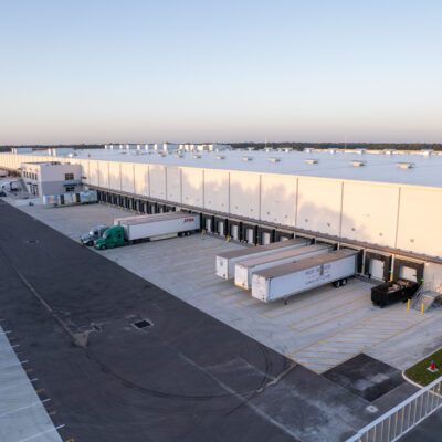 A large modern warehouse with multiple loading docks and trailers.