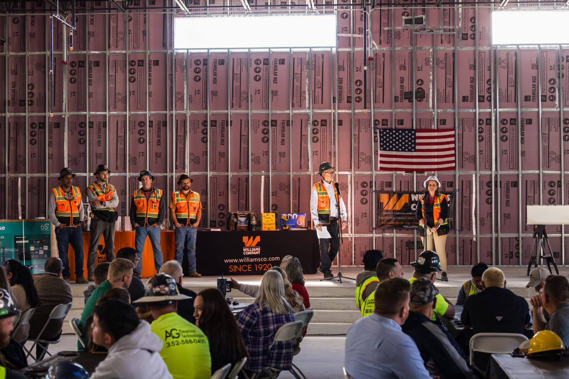 People attending a presentation in a construction setting with safety gear.